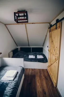 a room with two beds and a door in a attic at Zacisze Krzeszów in Krzeszów