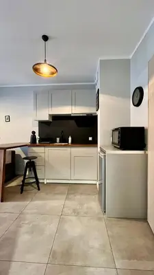 a kitchen with white cabinets and a table and a microwave at Small Apartment in Kraków