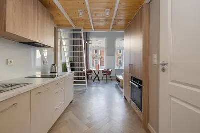 a kitchen with white cabinets and wooden ceilings and a dining room at Modern apartment -Berka Joselewicza 5 street in Kraków