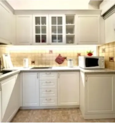 a white kitchen with white cabinets and a microwave at Jubilat Apartament in Kraków