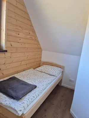 a bed in a room with a wooden wall at Domek Pod Babim Szczytem in Zubrzyca Górna