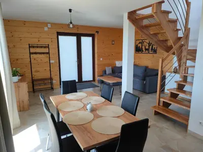 a dining room with a table and chairs and a staircase at Domek Pod Babim Szczytem in Zubrzyca Górna