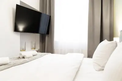 a white bedroom with a flat screen tv on the wall at Househost Apartment Zacisze 16 in Kraków