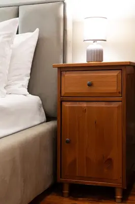 a nightstand with a lamp on it next to a bed at Househost Apartment Zacisze 16 in Kraków