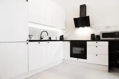 a kitchen with white cabinets and black appliances at Househost Apartment Zacisze 16 in Kraków