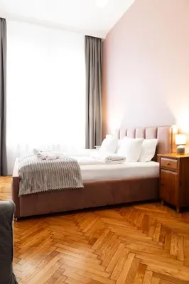 a bedroom with a large bed and a wooden floor at Househost Apartment Zacisze 16 in Kraków