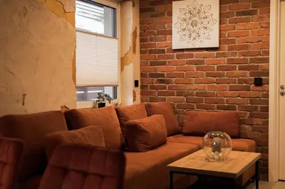 a brown couch in a room with a brick wall at Domki Natura Zator in Graboszyce
