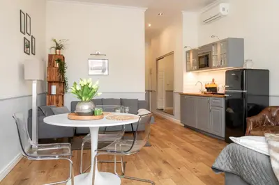a kitchen and a living room with a table and chairs at Malila Premium Apartments Szczepański Square in Kraków