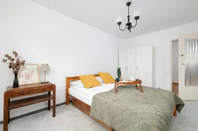 a bedroom with a bed and a nightstand with a table at Cozy Apartment with Balcony in Cracow by Noclegi Renters in Kraków
