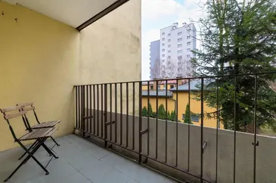 a balcony with a chair and a view of a building at Cozy Apartment with Balcony in Cracow by Noclegi Renters in Kraków