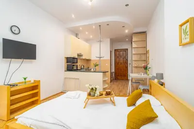 a bedroom with a large bed and a kitchen at Piasek Studio - Old Town nearby - by Rentujemy in Kraków