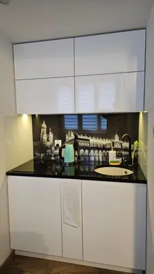 a kitchen with white cabinets and a black counter top at NextToNobu in Kraków