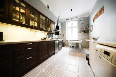 a large kitchen with brown cabinets and a table at Urban Nest Apartments Radziwiłłowska 17 in Kraków