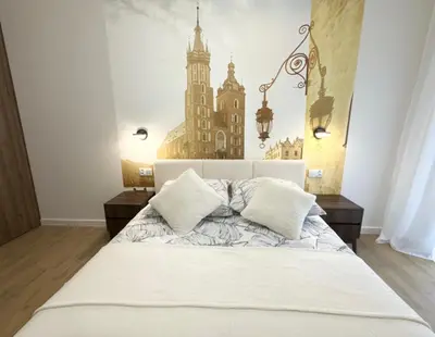 a bedroom with a large white bed with a building mural on the wall at Wawel Riverside Apartment free Parking in Kraków