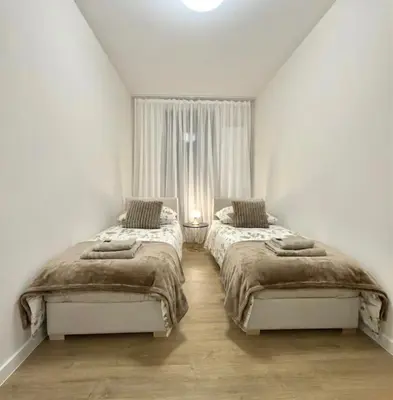 two beds in a white room with a window at Wawel Riverside Apartment free Parking in Kraków