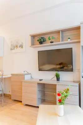 a living room with a desk with a tv on a wall at Krakow Old Town Studio N1 - by Rentujemy in Kraków