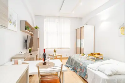 a white living room with a bed and a table at Krakow Old Town Studio N1 - by Rentujemy in Kraków