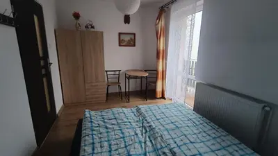 a bedroom with a bed and a table and a window at Noclegi pod Sosnowym Drzewem in Pieskowa Skała