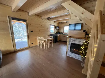 a living room with a table and a fireplace at Domki na granicy - Kurów in Kurów