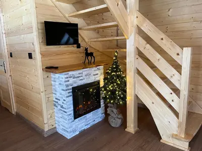 a living room with a fireplace and a christmas tree at Domki na granicy - Kurów in Kurów