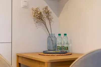 a vase with flowers and bottles on a table at Cracow Novum Apartment #533 by BookingHost in Kraków
