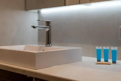 a bathroom sink with a faucet and two blue glasses at Cracow Novum Apartment #533 by BookingHost in Kraków