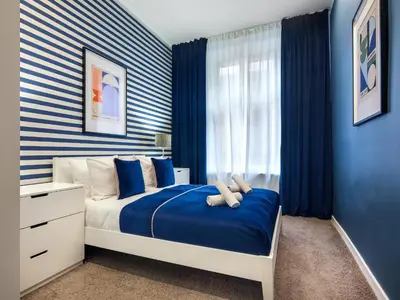 a bedroom with a bed with blue walls and blue curtains at Gentle Glow Suite by Tyzenhauz in Kraków