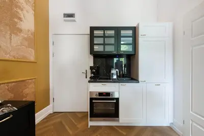 a kitchen with white cabinets and a microwave at Gentle Glow Suite by Tyzenhauz in Kraków