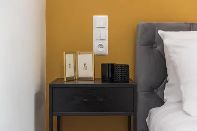 a bed with a black night stand next to a bed at Gentle Glow Suite by Tyzenhauz in Kraków