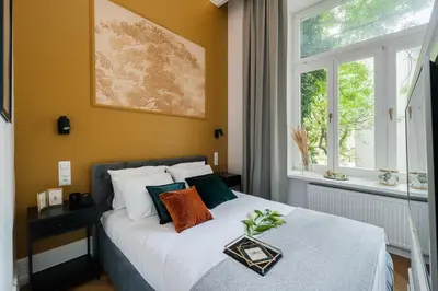 a bedroom with a bed with white sheets and a window at Gentle Glow Suite by Tyzenhauz in Kraków