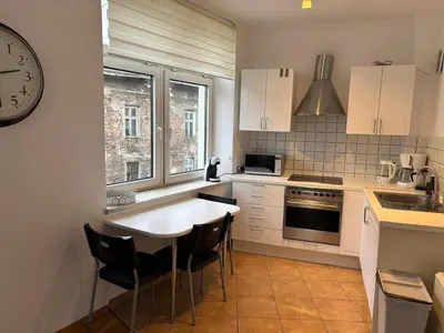 a kitchen with a table and a clock on the wall at Apartment Warszauera 3 in Kraków