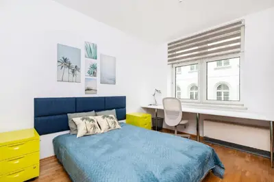 a bedroom with a blue bed and a desk at Apartment Warszauera 3 in Kraków