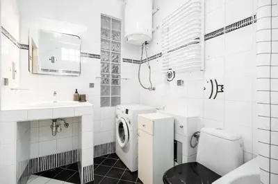 a white bathroom with a washing machine and a sink at Apartment Warszauera 3 in Kraków