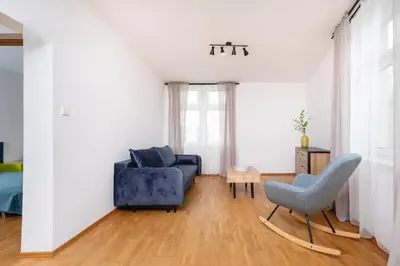 a living room with a blue couch and a chair at Apartment Warszauera 3 in Kraków