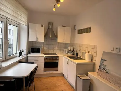 a kitchen with white cabinets and a table in it at Apartment Warszauera 3 in Kraków