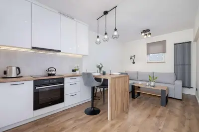 a kitchen with white cabinets and a table in a room at Paulińska 30 Kraków Spacious Apartment Kazimierz in Kraków