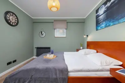 a bedroom with a large bed and a clock on the wall at Paulińska 30 Kraków Spacious Apartment Kazimierz in Kraków