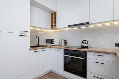 a kitchen with white cabinets and a black oven at Paulińska 30 Kraków Spacious Apartment Kazimierz in Kraków