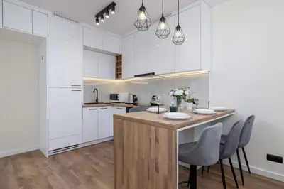 a kitchen with white cabinets and a wooden island with chairs at Paulińska 30 Kraków Spacious Apartment Kazimierz in Kraków