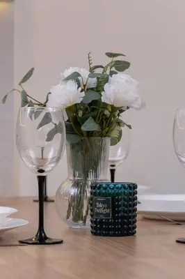 a vase with white flowers and a candle on a table at Paulińska 30 Kraków Spacious Apartment Kazimierz in Kraków