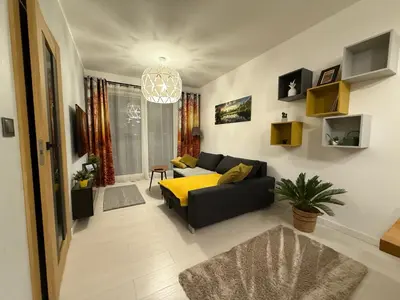 a living room with a black couch and a yellow blanket at Wiślane Pianissimo apartament in Kraków