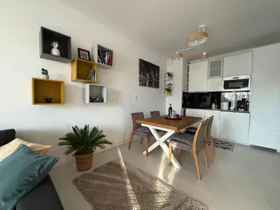 a kitchen and dining room with a table and chairs at Wiślane Pianissimo apartament in Kraków