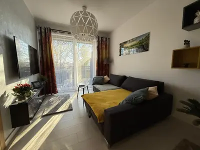 a living room with a couch and a large window at Wiślane Pianissimo apartament in Kraków