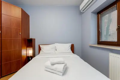 a bedroom with a bed with white sheets and a window at Cracow Vistula Harmony Apartment by BookingHost in Kraków
