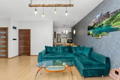 a living room with a green couch and a glass table at Cracow Vistula Harmony Apartment by BookingHost in Kraków
