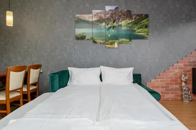 a bed in a room with three paintings on the wall at Cracow Vistula Harmony Apartment by BookingHost in Kraków
