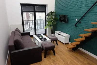 a living room with a couch and chairs and a staircase at Apartament Elementos in Kraków