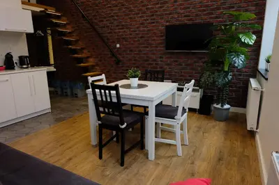 a white table and chairs in a kitchen with a brick wall at Apartament Elementos in Kraków