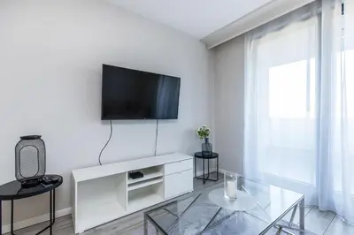 a white living room with a tv on a wall at Riva Cracovia in Kraków