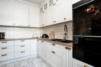a white kitchen with white cabinets and a sink at Wroblewskiego No 4 Residence in Kraków
